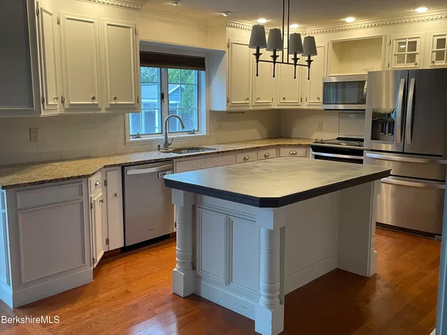 a kitchen with kitchen island granite countertop a sink cabinets and stainless steel appliances