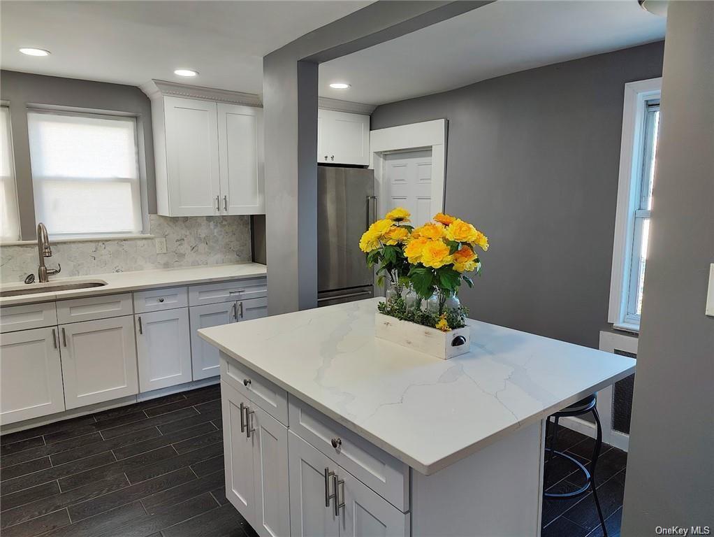 a kitchen with stainless steel appliances a white sink cabinets and wooden floor