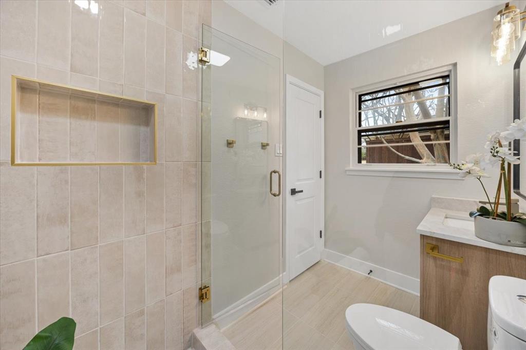 10524 Coleridge Street Dallas, TX 75218 - Photo 12 of 35 a bathroom with a granite countertop sink a mirror a toilet and shower