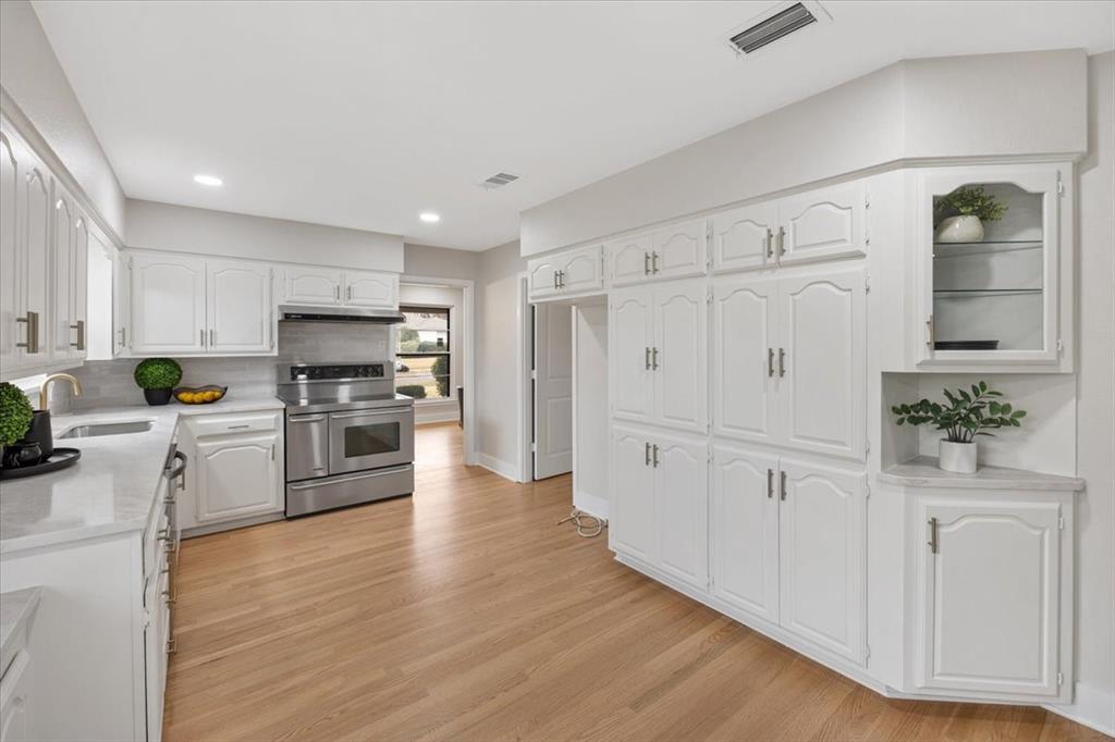 10524 Coleridge Street Dallas, TX 75218 - Photo 24 of 35 a kitchen with white cabinets and wooden floor