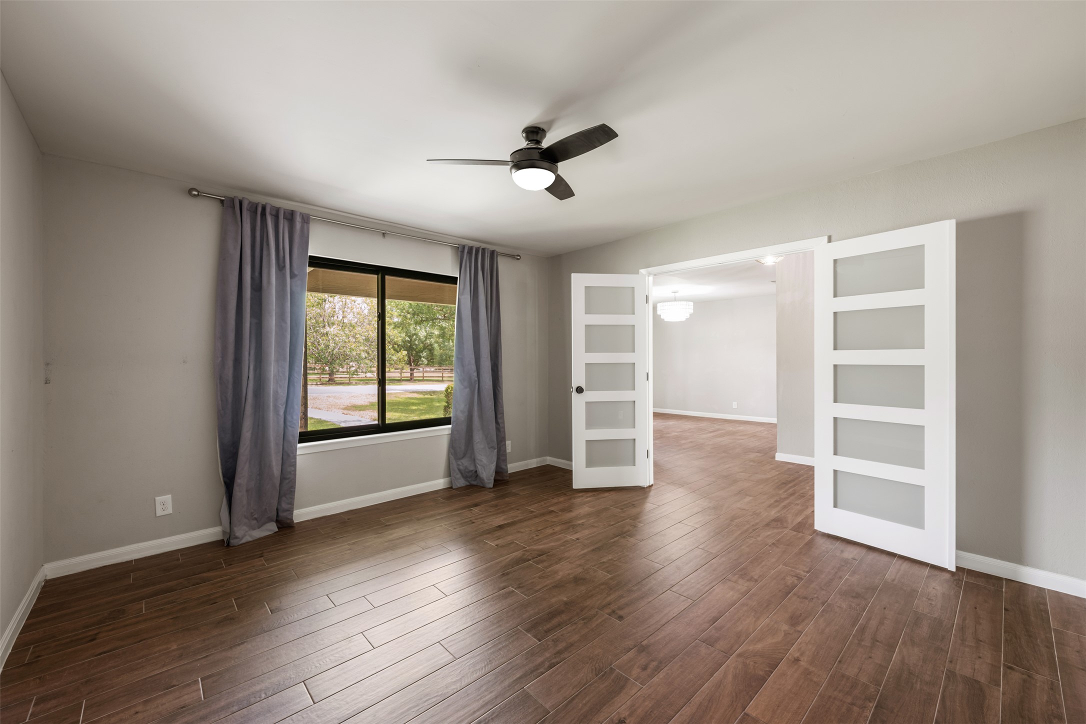 1600 Pin Oak Lane Round Rock, TX 78681 - Photo 6 of 40 Spacious room featuring wood-finish flooring, a contemporary ceiling fan with integrated lighting, and a large window