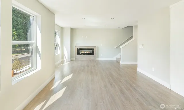 a view of a big room with wooden floor fireplace and windows