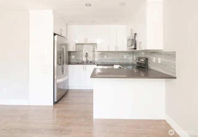 a kitchen with kitchen island granite countertop a sink and a refrigerator