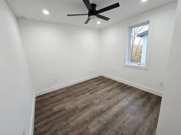 an empty room with a window and a ceiling fan
