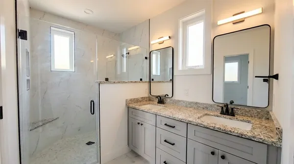 a bathroom with a granite countertop sink a mirror and shower