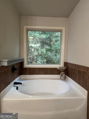 a white bath tub sitting in a bathroom next to a window