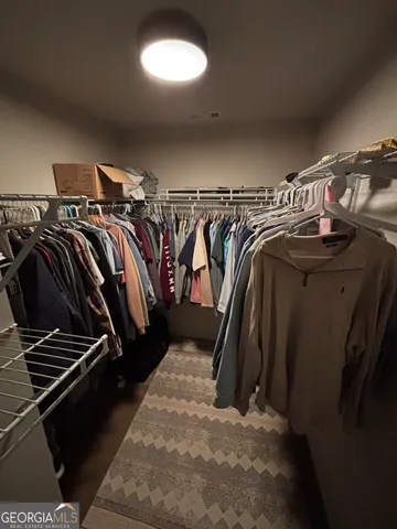 a view of walk in closet with clothes and shoes