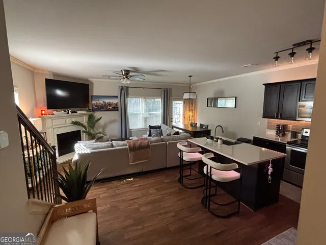 a living room with furniture a flat screen tv and kitchen view