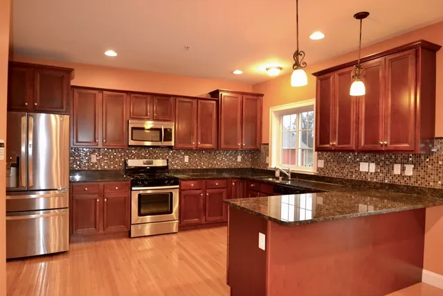 a kitchen with kitchen island granite countertop a sink stainless steel appliances and cabinets