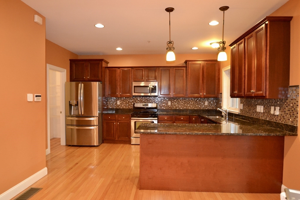 8 Cheyenne Valley, Unit 8 Westford, MA 01886 - Photo 6 of 27 a kitchen with stainless steel appliances granite countertop a refrigerator a sink dishwasher a stove and a microwave oven with wooden floor