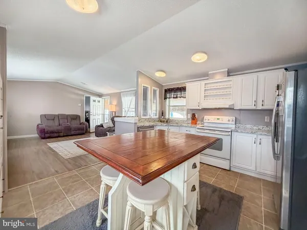 a kitchen with stainless steel appliances granite countertop a sink a stove a refrigerator cabinets and living room view