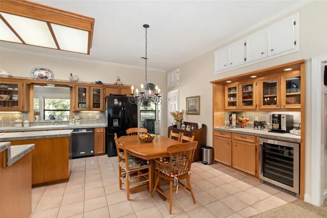 a kitchen with stainless steel appliances granite countertop a stove top oven a sink a dining table and chairs with white cabinets