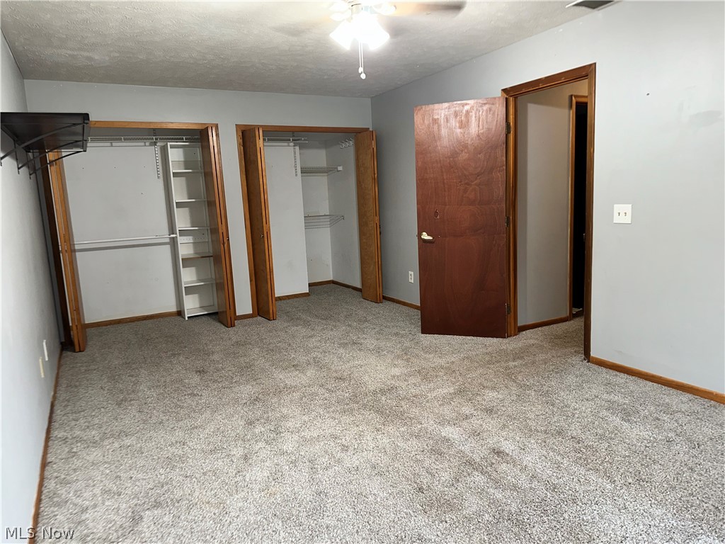7495 Johnnycake Ridge Road Mentor, OH 44060 - Photo 26 of 50 Unfurnished bedroom with a textured ceiling, two closets, ceiling fan, and light colored carpet