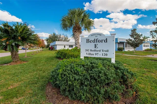 a sign of golf club on a wall under a tree