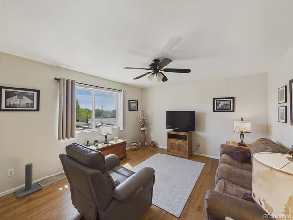 a living room with furniture a flat screen tv and wooden floor