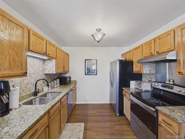 a kitchen with granite countertop a sink stove and cabinets