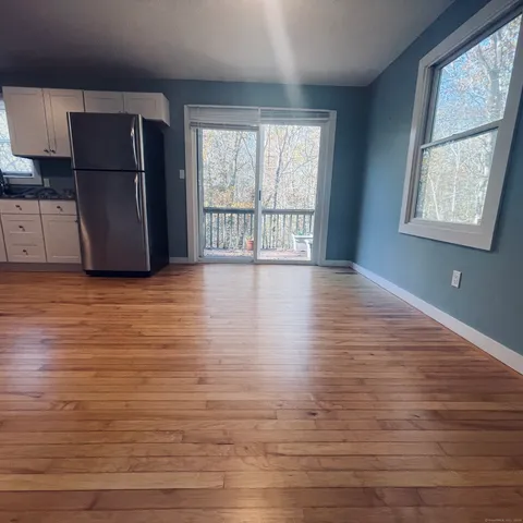 a view of an empty room with a window and wooden floor