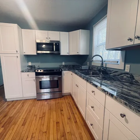 a kitchen with stainless steel appliances granite countertop a stove a sink and white cabinets