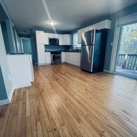 a view of kitchen with refrigerator stove and wooden floor