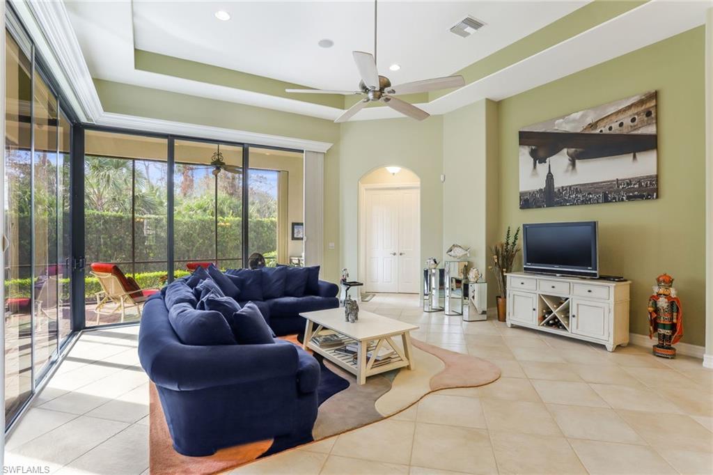 7433 Byrons Way Naples, FL 34113 - Photo 14 of 34 a living room with furniture a flat screen tv and a floor to ceiling window
