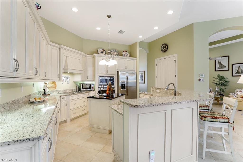 7433 Byrons Way Naples, FL 34113 - Photo 17 of 34 a kitchen with stainless steel appliances granite countertop a sink stove and cabinets