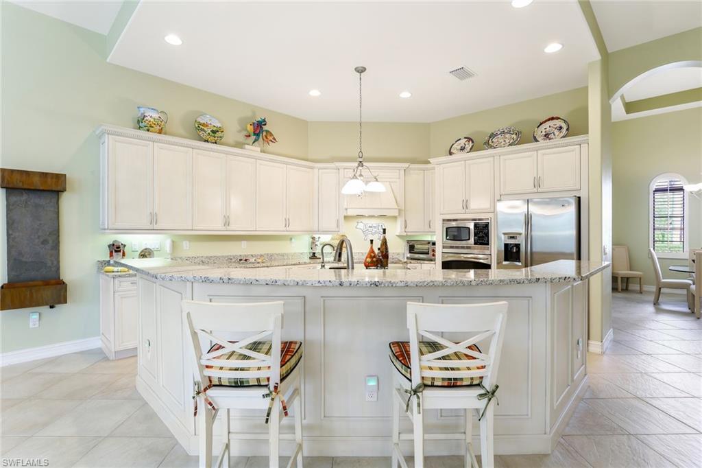 7433 Byrons Way Naples, FL 34113 - Photo 18 of 34 a kitchen with stainless steel appliances kitchen island granite countertop a table and chairs in it