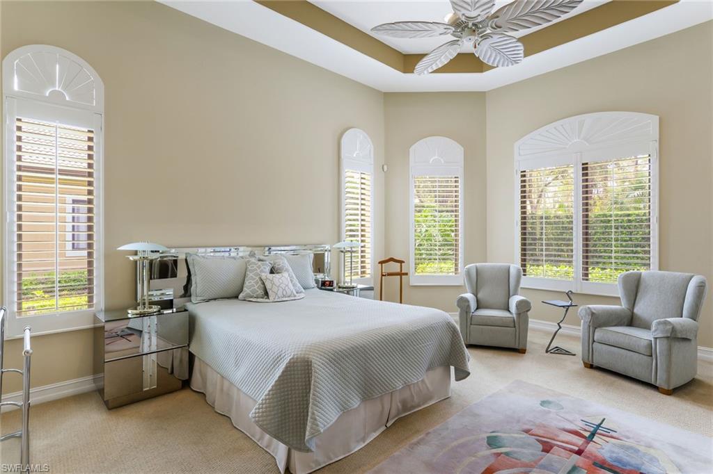 7433 Byrons Way Naples, FL 34113 - Photo 20 of 34 a spacious bedroom with a bed a couch and a chandelier