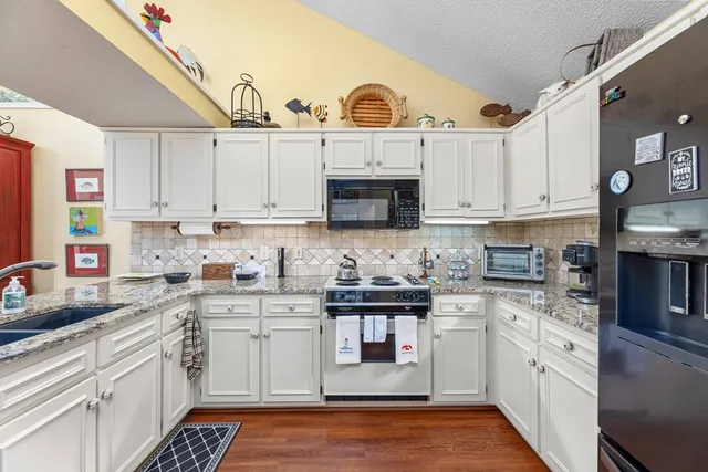 a kitchen with stainless steel appliances granite countertop a sink a stove and cabinets