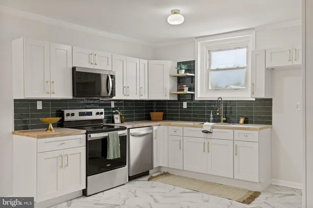 a kitchen with stainless steel appliances granite countertop white cabinets sink and window
