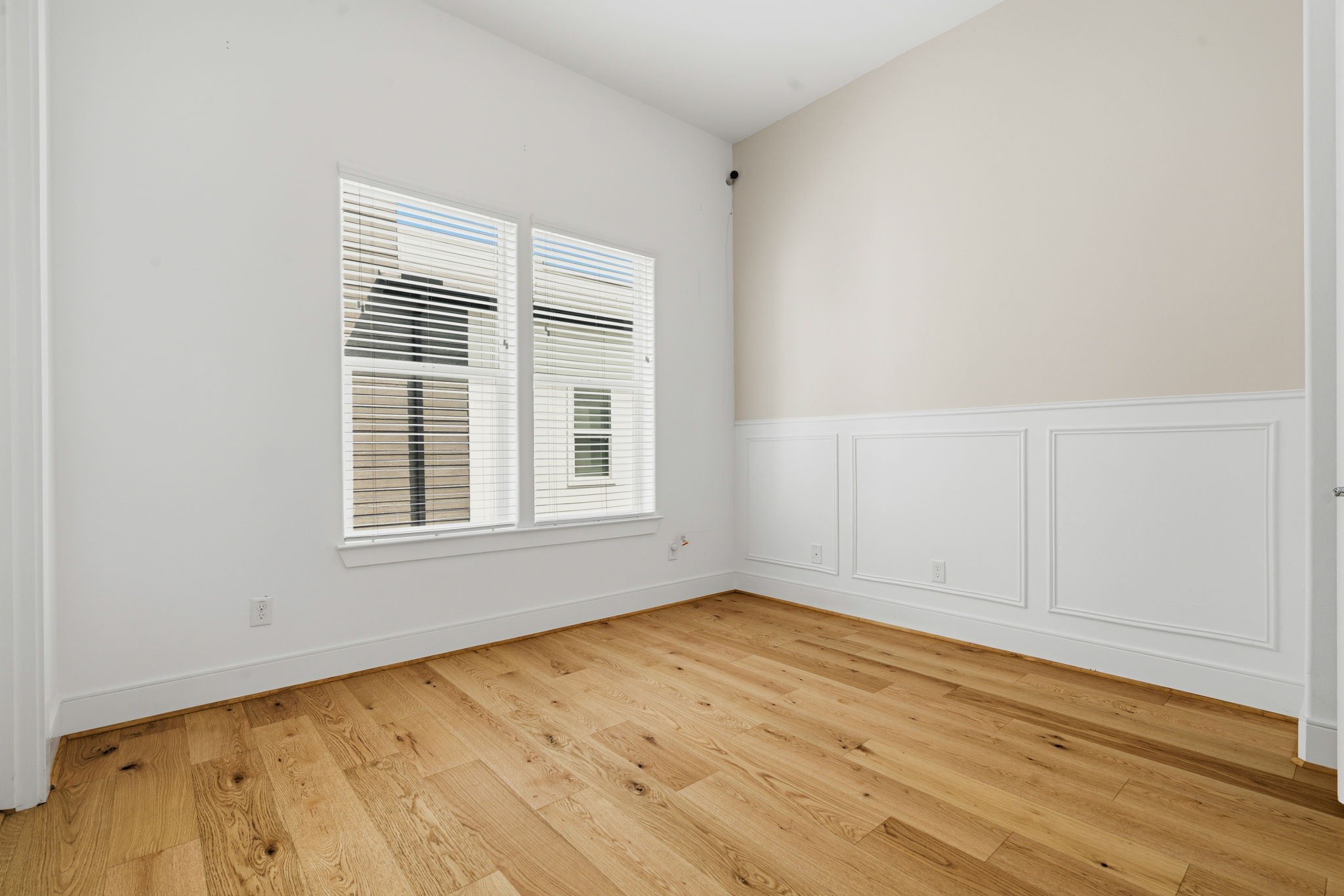 2624 Rusk Street Houston, TX 77003 - Photo 27 of 30 Bright and inviting bedroom featuring elegant wainscoting and beautiful hardwood floors, perfect for relaxation.