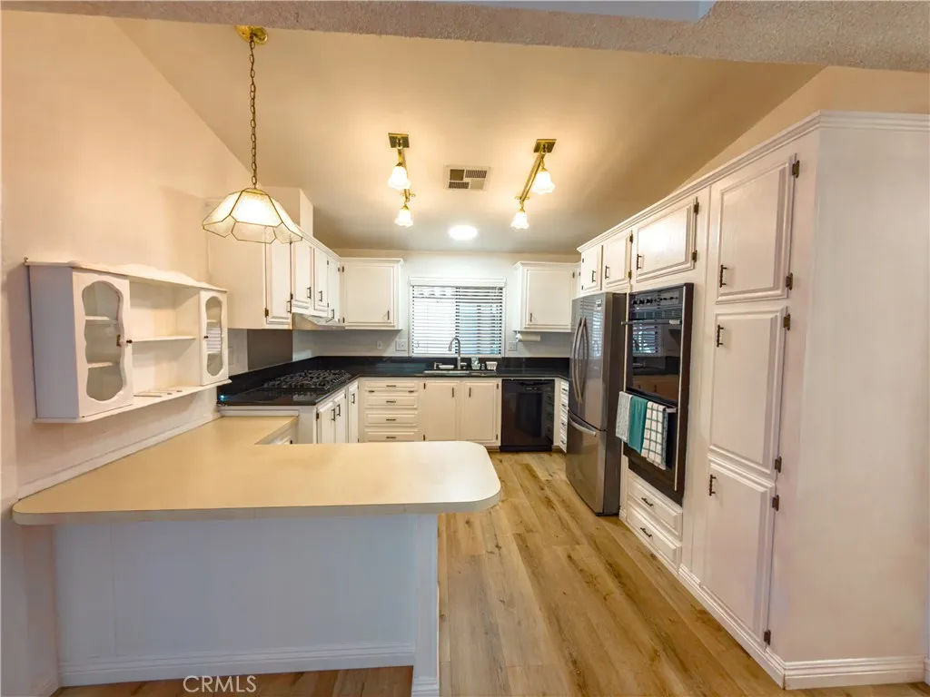 840 East Foothill Boulevard, Unit 203 Azusa, CA 91702 - Photo 16 of 45 a kitchen with stainless steel appliances a refrigerator a stove a sink dishwasher and white cabinets with wooden floor