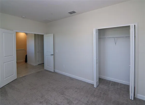 a view of an empty room with closet and bathroom