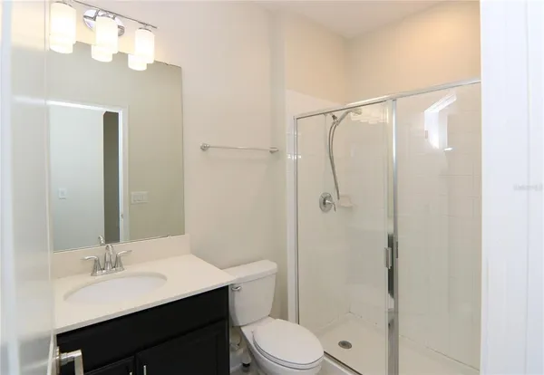 a bathroom with a sink a toilet a mirror and shower