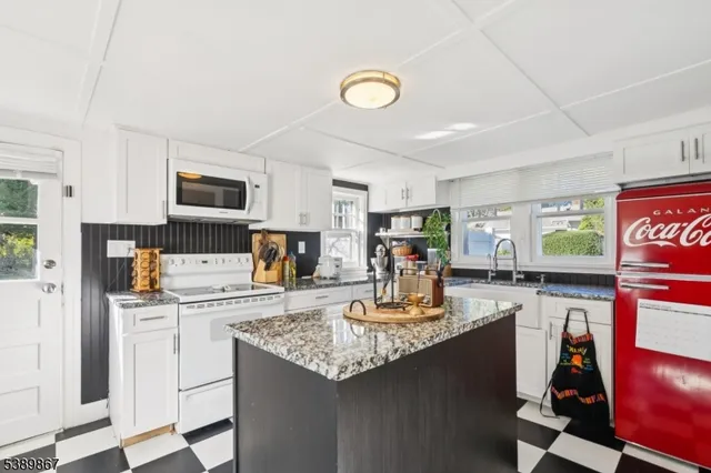 a kitchen with kitchen island granite countertop a sink appliances cabinets and furniture