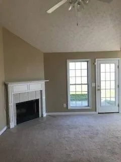 an empty room with windows and fireplace