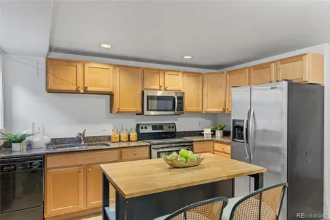 a kitchen with stainless steel appliances granite countertop a refrigerator a stove a sink a dining table and chairs