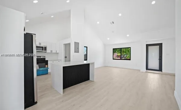 a view of kitchen with stainless steel appliances kitchen island wooden floors and cabinets