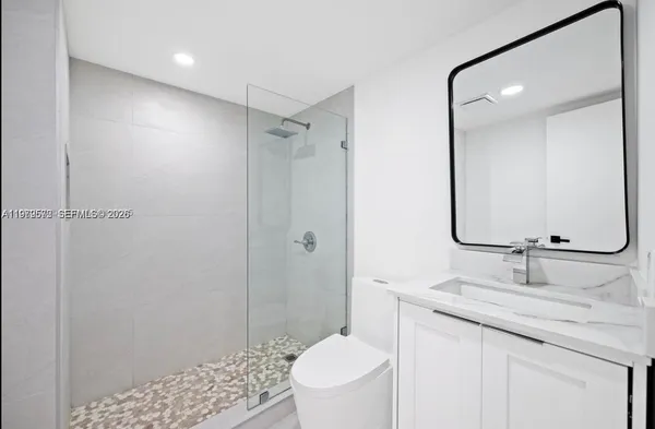 a bathroom with a granite countertop sink a toilet and shower