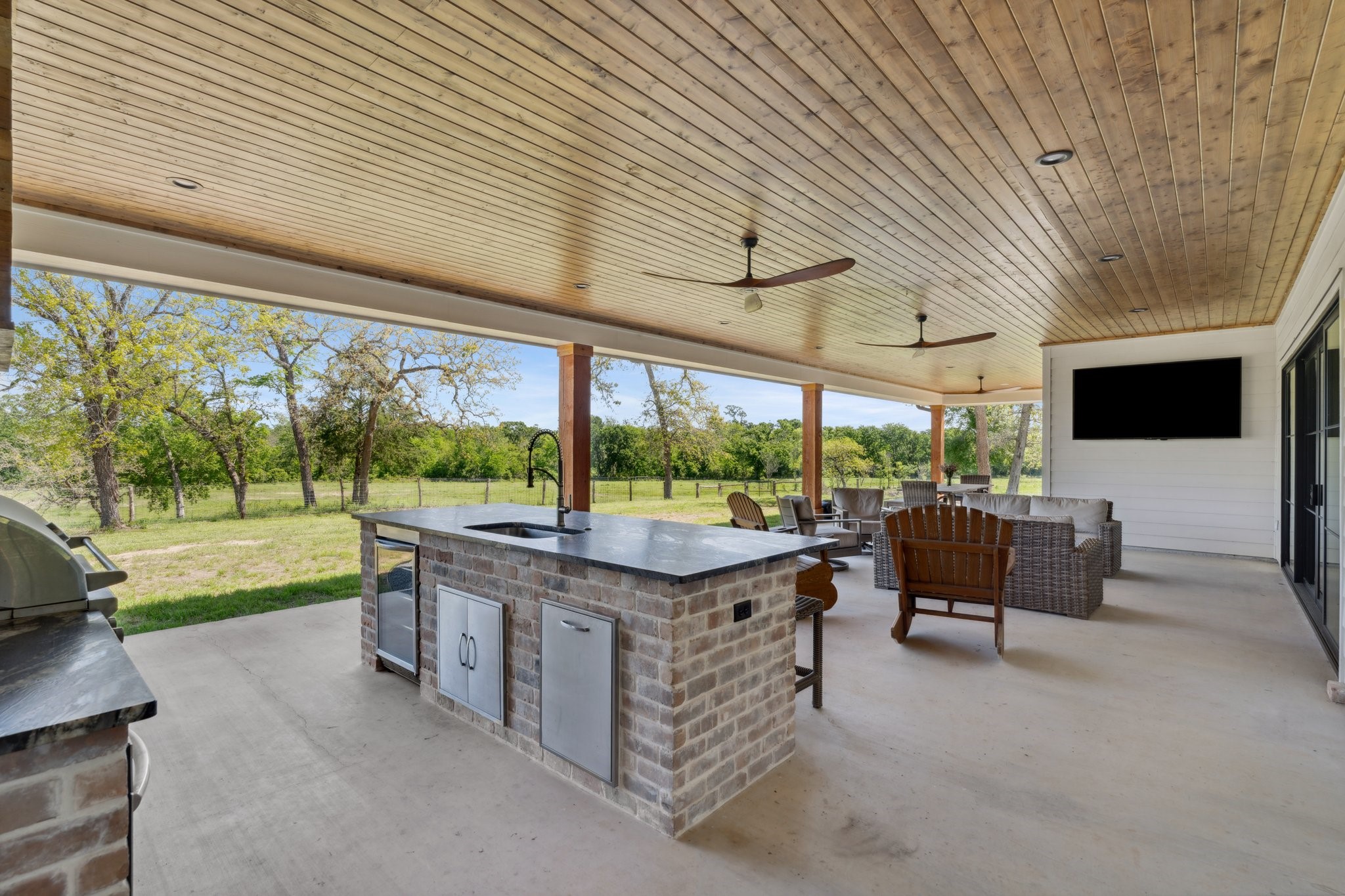 4052 Kuykendall Road Bellville, TX 77418 - Photo 13 of 40 Transform your gatherings with this stunning outdoor oasis featuring a Coyote grill, Frigidaire appliances, a mounted TV, spacious seating, and even an outdoor bathroom and shower—perfect for entertaining in style!