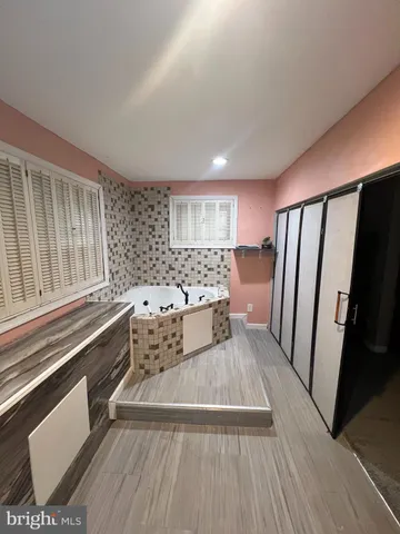 a large white kitchen with a large window a refrigerator and wooden floor