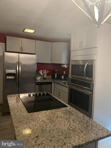 a kitchen with granite countertop a refrigerator and a stove