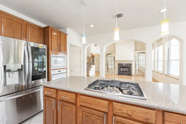 a kitchen with stainless steel appliances kitchen island granite countertop a refrigerator and a stove top oven