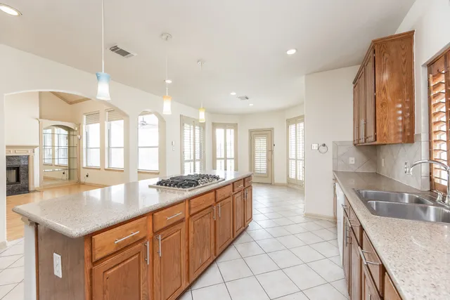 a kitchen with stainless steel appliances granite countertop a sink a stove and a wooden cabinets