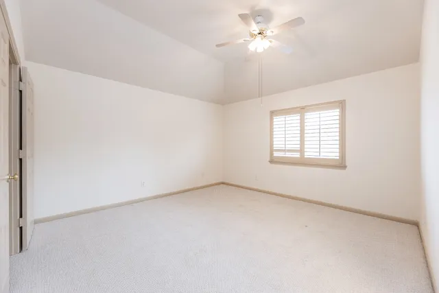 an empty room with a window and a ceiling fan