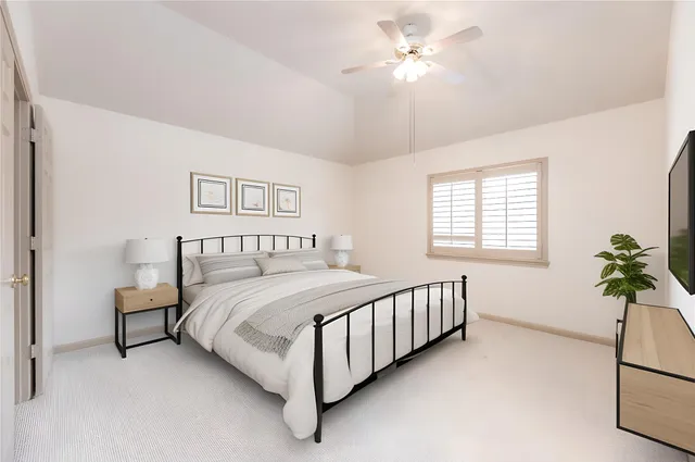 a bedroom with a large bed and a chandelier fan