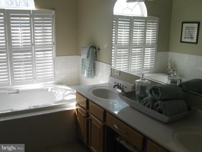 44886 Mallard Place Callaway, MD 20620 - Photo 21 of 30 a bathroom with a granite countertop sink and a bathtub