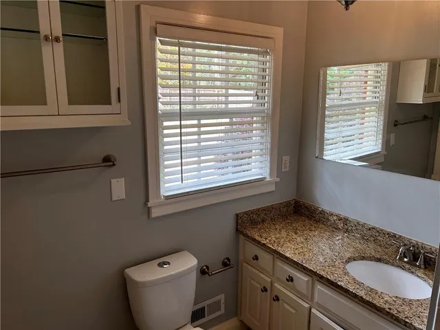 a bathroom with a granite countertop sink toilet and mirror
