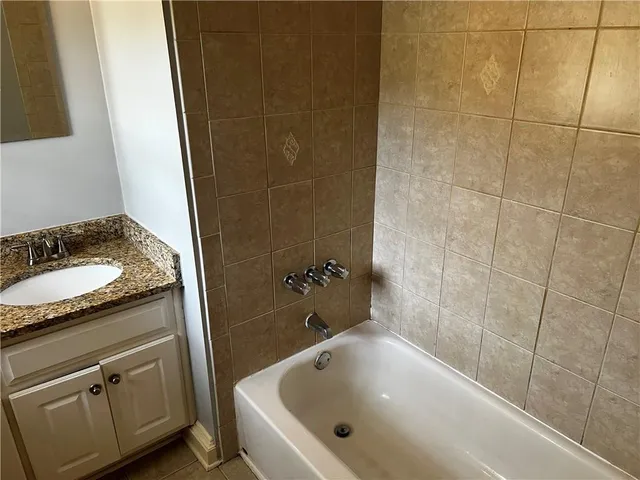 a bathroom with a granite countertop sink and a bathtub