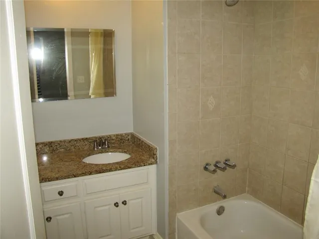 a bathroom with a granite countertop sink and tub