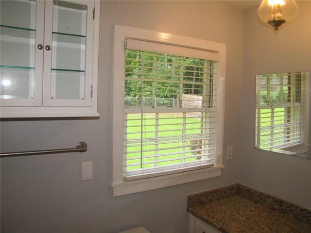 a bathroom with a granite countertop toilet a sink and a window
